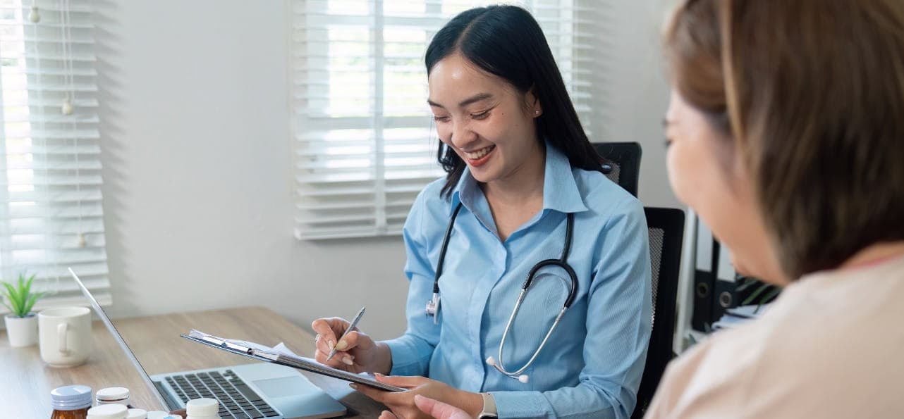 General physician consulting a patient in a modern clinic, friendly interaction, clean medical environment, professional healthcare setting, realistic lighting, no text in image